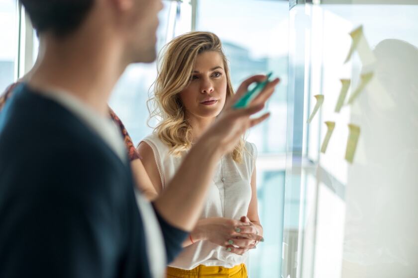 Une entrepreneure présente son plan devant un mur d’idées.