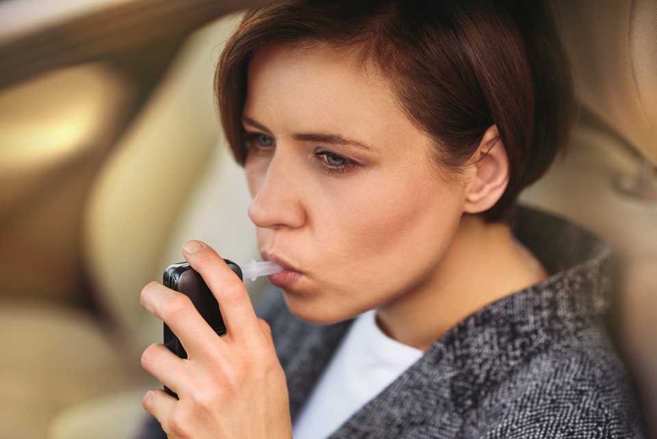 Woman taking breathalyzer test in the car